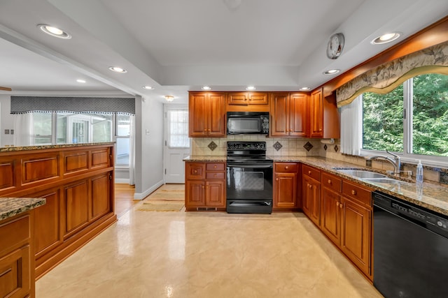 kitchen featuring brown cabinets, black appliances, a sink, light stone counters, and backsplash