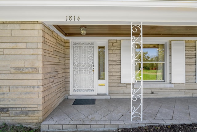 property entrance with stone siding and a porch