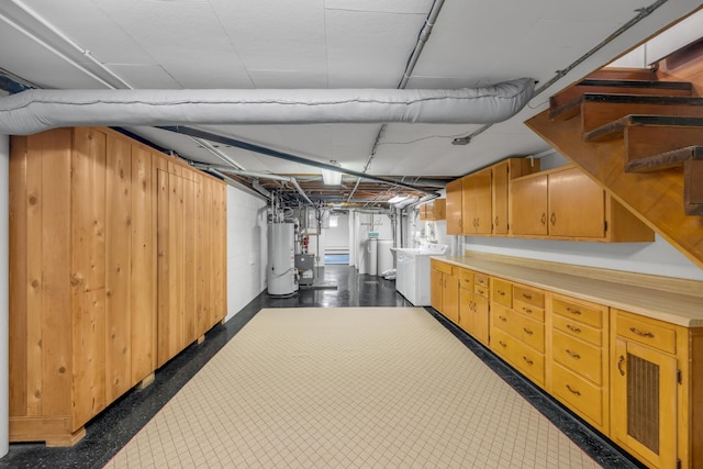 basement featuring washing machine and clothes dryer, wooden walls, gas water heater, and stairway