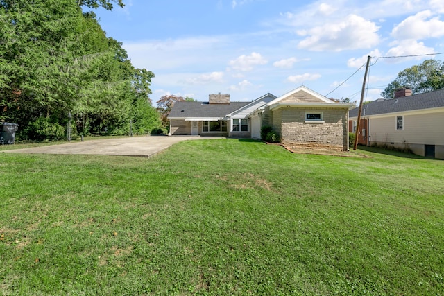 rear view of property with a patio area, concrete driveway, and a yard