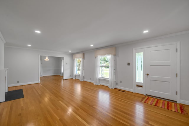 foyer with visible vents, baseboards, crown molding, and light wood-style floors