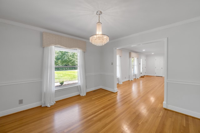spare room with a chandelier, light wood-style flooring, baseboards, and ornamental molding