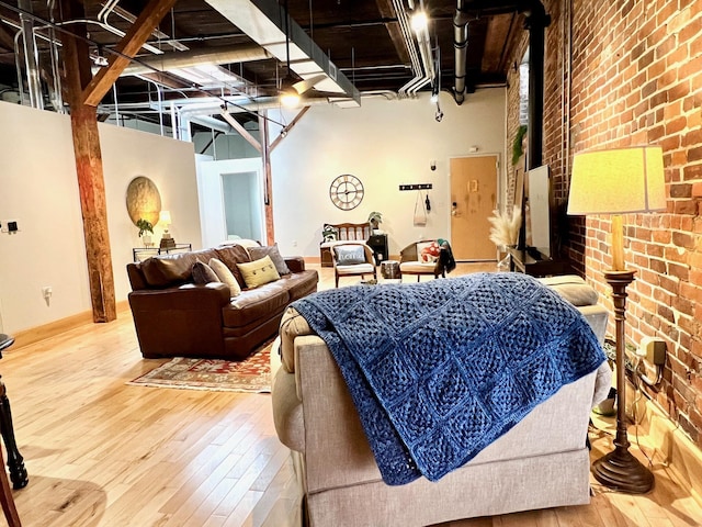 living room with hardwood / wood-style floors, a high ceiling, and brick wall