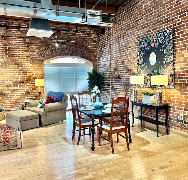 dining room with brick wall, a high ceiling, and wood finished floors