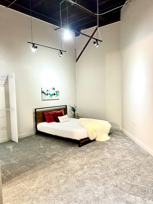 bedroom with a high ceiling, baseboards, and carpet floors