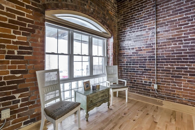 living area with brick wall and hardwood / wood-style floors