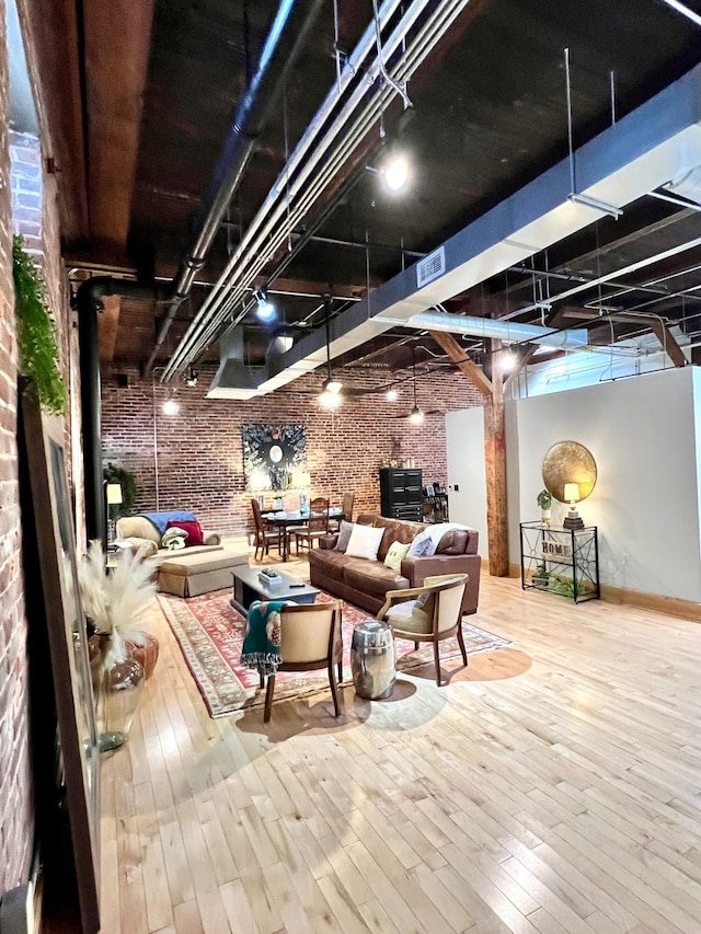 interior space with rail lighting, wood-type flooring, visible vents, and brick wall
