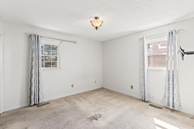 carpeted empty room with baseboards, a textured ceiling, and visible vents