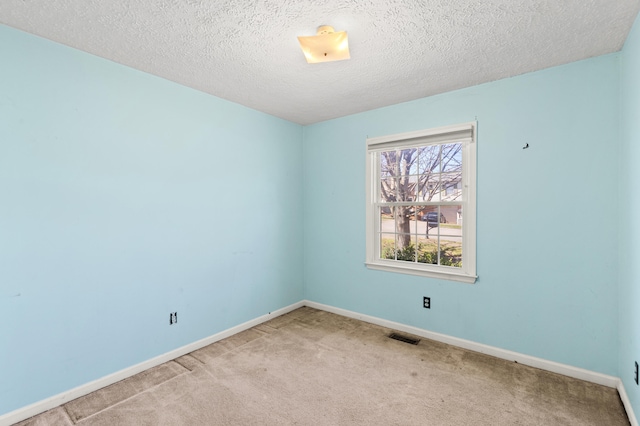 carpeted empty room featuring visible vents, baseboards, and a textured ceiling