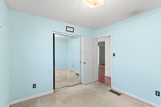 unfurnished bedroom with a closet, carpet, visible vents, and baseboards