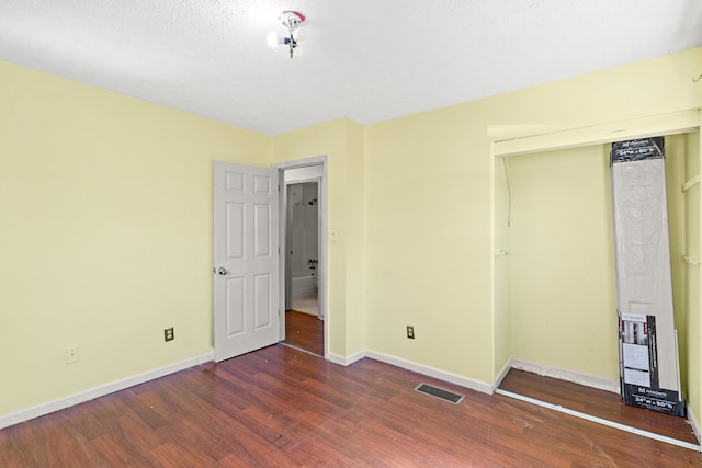 unfurnished bedroom featuring baseboards, wood finished floors, visible vents, and a closet