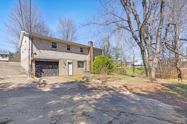 view of front of home featuring a chimney, driveway, a vegetable garden, an attached garage, and stucco siding