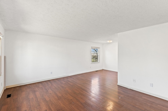 unfurnished room with baseboards, visible vents, a textured ceiling, and dark wood-style floors