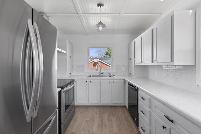 kitchen with a sink, light countertops, appliances with stainless steel finishes, white cabinetry, and light wood-type flooring