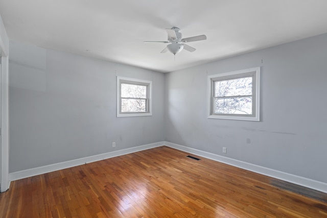 spare room with a ceiling fan, hardwood / wood-style flooring, baseboards, and visible vents