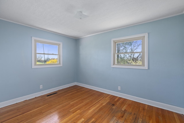 empty room with a textured ceiling, baseboards, and hardwood / wood-style flooring