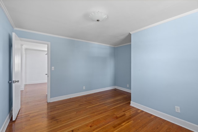 empty room with baseboards, wood finished floors, and crown molding