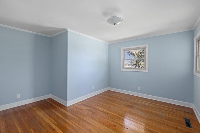 spare room with baseboards, wood-type flooring, and ornamental molding