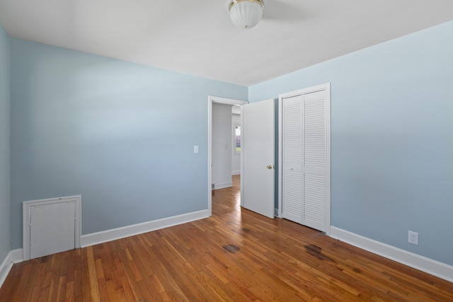 unfurnished bedroom featuring a closet, baseboards, and hardwood / wood-style flooring