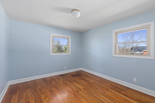 unfurnished room featuring visible vents, baseboards, and hardwood / wood-style flooring