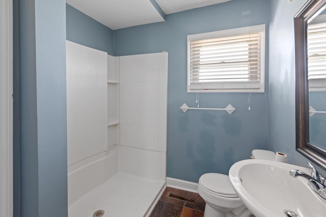 full bath featuring visible vents, baseboards, a sink, walk in shower, and toilet