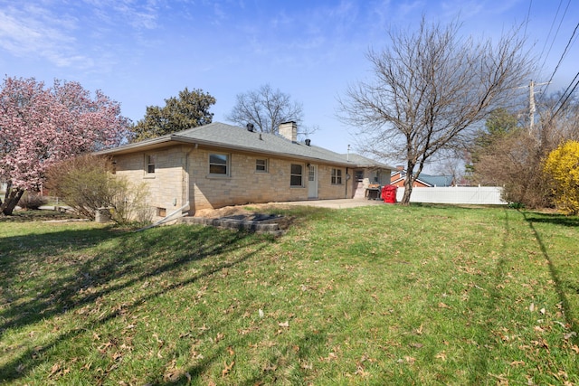 back of house with fence, a yard, roof with shingles, a chimney, and a patio area