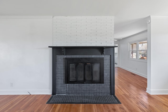 room details with baseboards, a brick fireplace, and wood finished floors