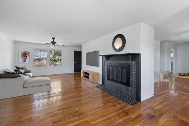 unfurnished living room featuring a fireplace, hardwood / wood-style floors, ceiling fan, and ornamental molding