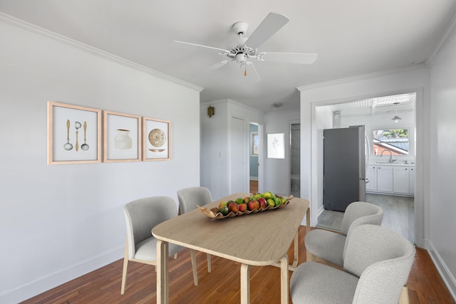dining area featuring baseboards, wood finished floors, a ceiling fan, and ornamental molding