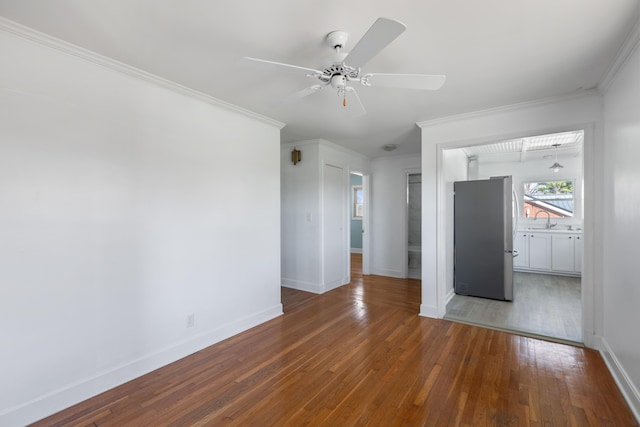 interior space with baseboards, ceiling fan, a sink, hardwood / wood-style flooring, and ornamental molding