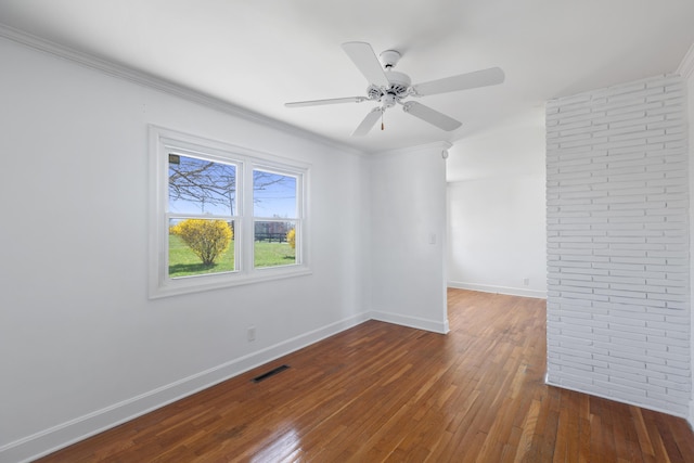 spare room with baseboards, visible vents, wood-type flooring, and ornamental molding