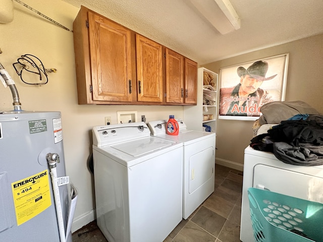 washroom featuring baseboards, washing machine and clothes dryer, dark tile patterned flooring, cabinet space, and water heater