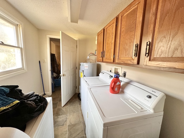 clothes washing area with washer and clothes dryer, cabinet space, water heater, and a textured ceiling
