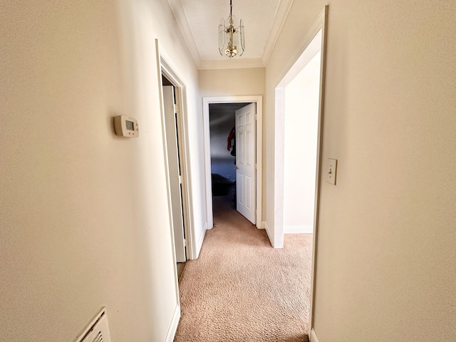 hall with a notable chandelier, baseboards, light colored carpet, and ornamental molding
