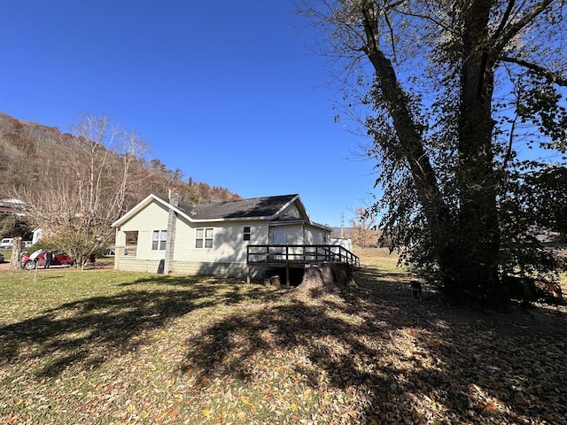 rear view of property featuring a wooden deck and a yard
