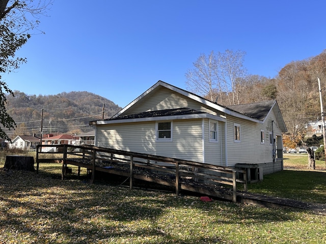 view of side of home featuring a yard, central AC, a mountain view, and fence