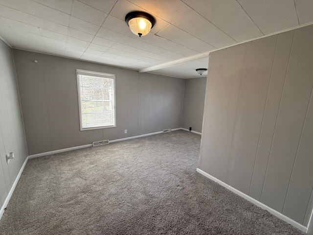 carpeted spare room featuring visible vents and baseboards