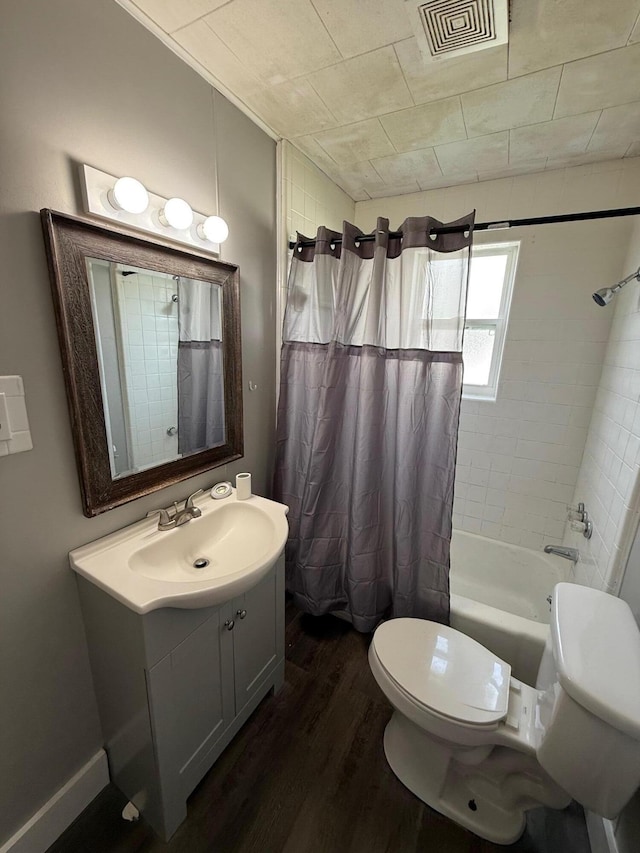 bathroom featuring toilet, wood finished floors, visible vents, and shower / bath combo