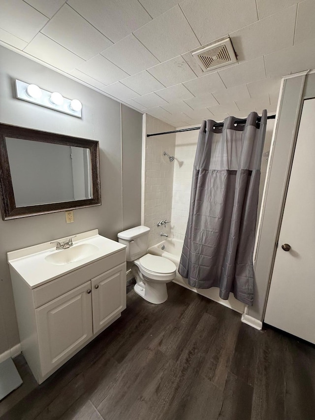 full bathroom with visible vents, toilet, shower / tub combo with curtain, wood finished floors, and vanity