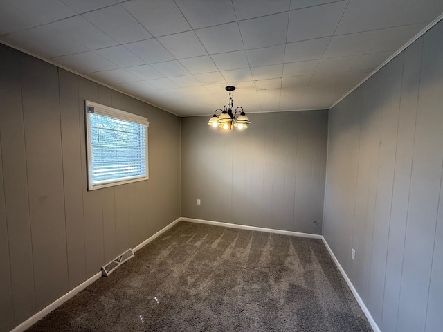 carpeted empty room featuring a notable chandelier, visible vents, and baseboards
