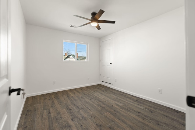 empty room featuring baseboards, visible vents, dark wood-style flooring, and a ceiling fan