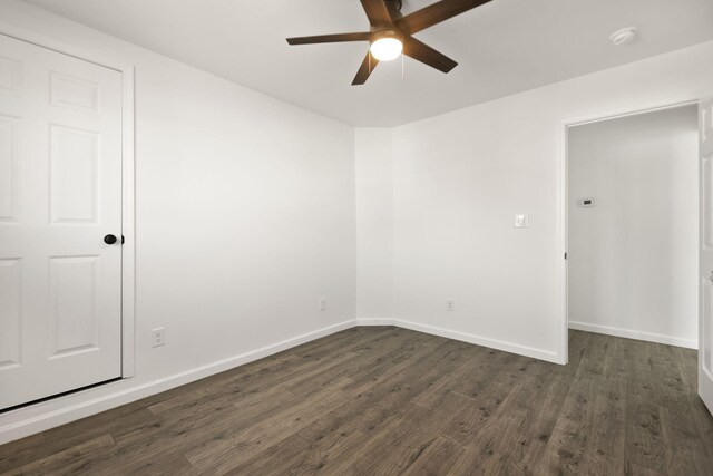 spare room with ceiling fan, baseboards, and dark wood-style floors