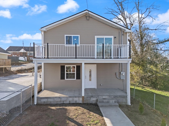 view of front facade with a porch, fence, and a balcony