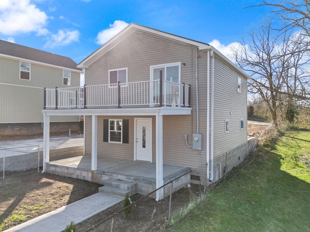 rear view of house featuring a yard, fence, and covered porch