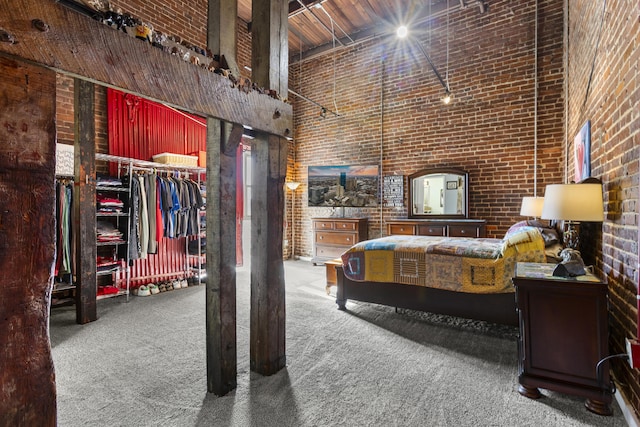 bedroom featuring carpet, a closet, a towering ceiling, and brick wall