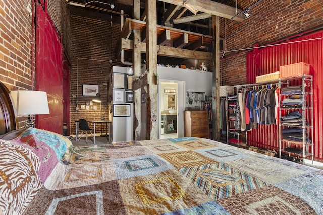 bedroom featuring a closet, a towering ceiling, and brick wall