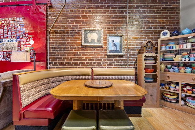 interior space featuring wood finished floors, breakfast area, and brick wall