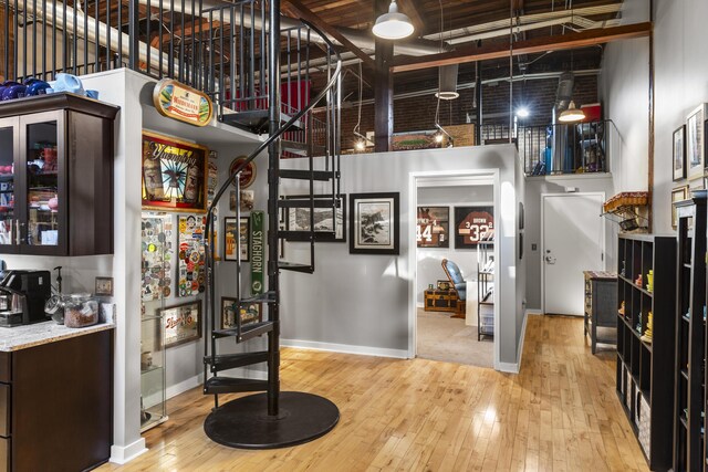 staircase featuring baseboards, a high ceiling, and hardwood / wood-style floors