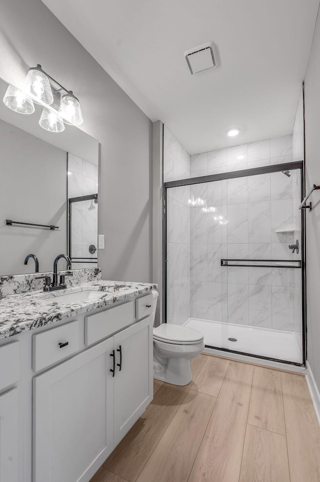 full bathroom featuring vanity, toilet, wood finished floors, visible vents, and a stall shower
