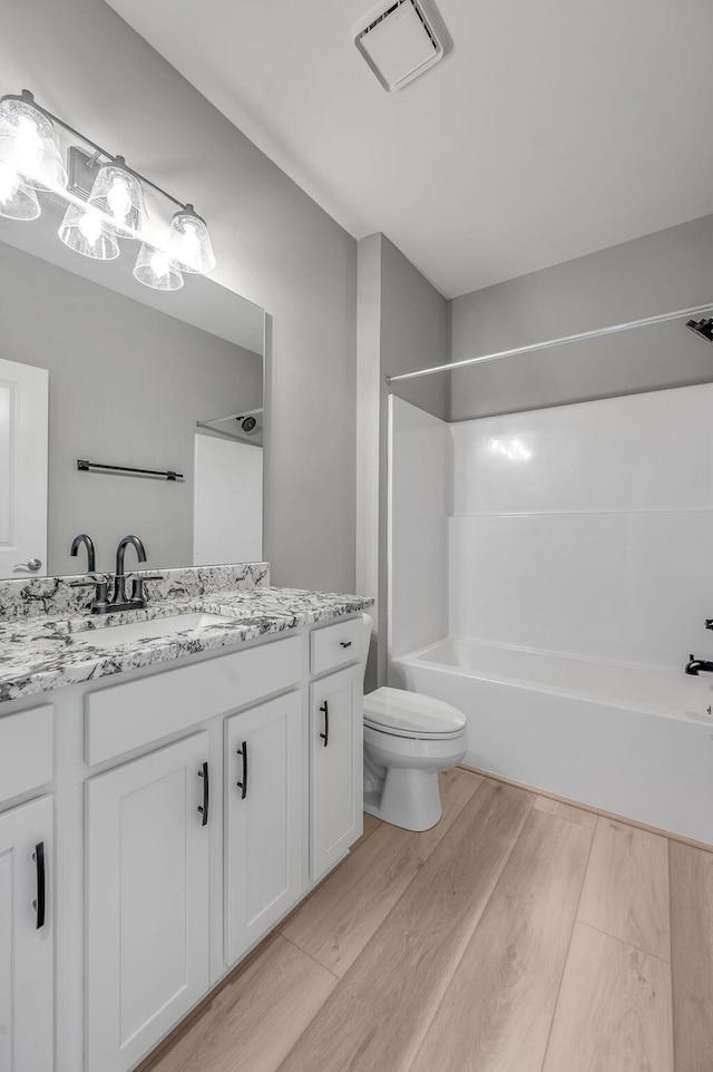 bathroom with visible vents, bathtub / shower combination, wood finished floors, vanity, and toilet